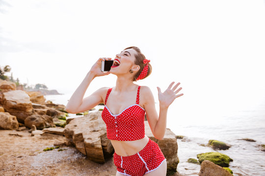 Pin up girl in red swimsuit talking on the phone