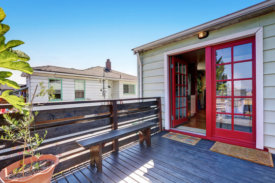 Wooden deck with a bench and red double door