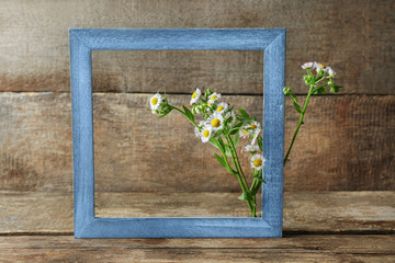 Retro frame with chamomile flowers on wooden background