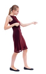 back view of standing girl pulling a rope from the top or cling to something. Isolated over white background. A girl in a burgundy dress clings to the rope.