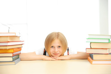 Smiling girl with many books at school