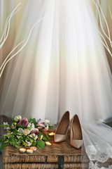 Shoes on wicker chest and wedding dress hanging on wall in room