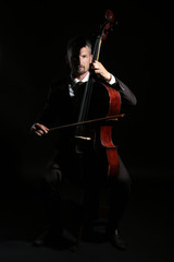Man playing cello in darkness