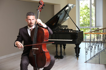 Fototapeta premium Man playing cello in room