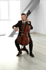 Man playing cello in room © Africa Studio