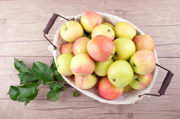 Fresh harvesting apples in basket on wooden table. Organic fruit