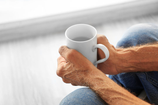 Old man holding cup of hot drink