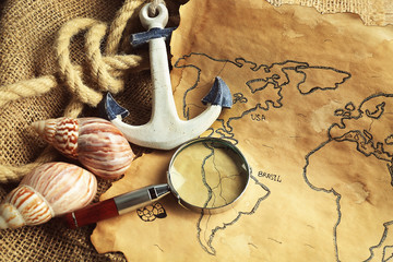 Magnifier, anchor and seashells on old map. Happy Columbus day concept