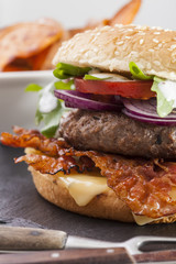 juicy  bacon cheese bbq burger on wooden table with fries