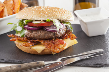 juicy  bacon cheese bbq burger on wooden table with fries