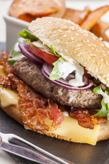 juicy  bacon cheese bbq burger on wooden table with fries