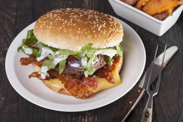 juicy  bacon cheese bbq burger on wooden table with fries