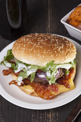 juicy  bacon cheese bbq burger on wooden table with fries