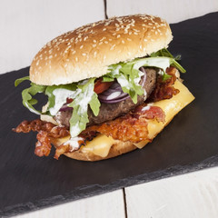 juicy  bacon cheese bbq burger on wooden table with fries