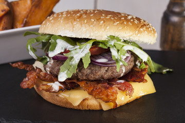 juicy  bacon cheese bbq burger on wooden table with fries