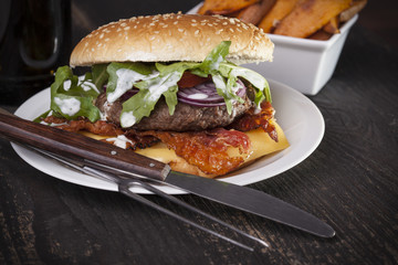 juicy  bacon cheese bbq burger on wooden table with fries