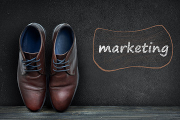 Marketing text on black board and business shoes