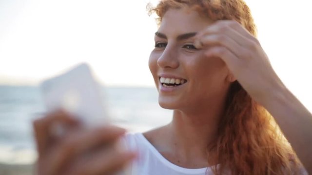 happy woman taking selfie with smartphone on beach