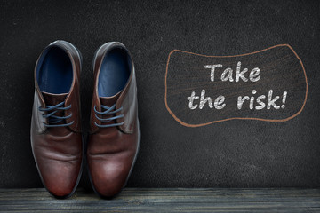 Take the risk text on black board and business shoes