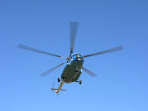 Helicopter in clear blue sky. Five propeller blades are blurred in motion.