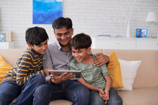 Indian Father And Sons Watching Movie On Tablet Computer