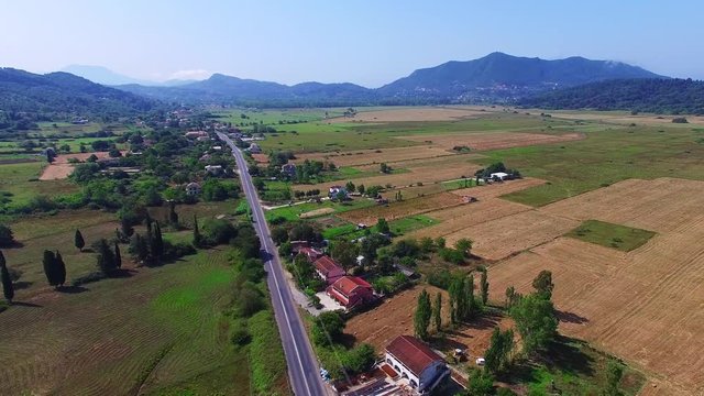 Countryside landscape 4k video. Aerial view of Greece ECO village, houses, fields, farm, road and mountain in background