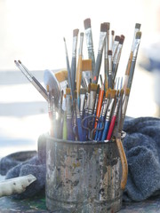 Close-up of paintbrushes in dirty old metal jar