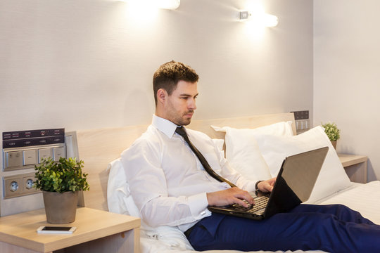 young businessman working for the laptop on the bed in the hotel