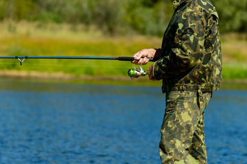 Naklejka premium fisherman with a fishing tackle catches a fish on the shore
