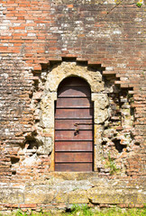 Old wooden door in aged brick wall