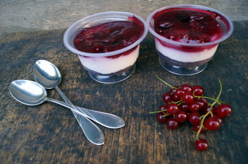 Parfait dessert with berries, milk souffle and jello layers. Treat in a glass on a rustic wooden background