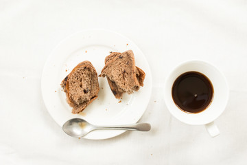 Top view of coffee and bread on white fabric background.
