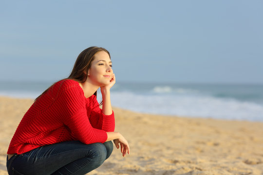 Confident pensive woman thinking on the beach