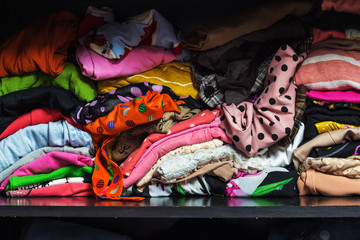 Pile of colorful clothes in a closet.