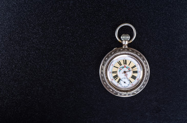 Old pocket watch on a black table