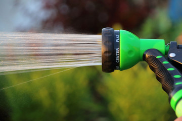 Watering flower bed with an adjustable shower (spray) in the summer evening garden