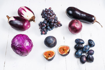 Collection of fresh purple fruit and vegetables on wooden background