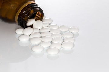 dragee pills and brown bottle white background