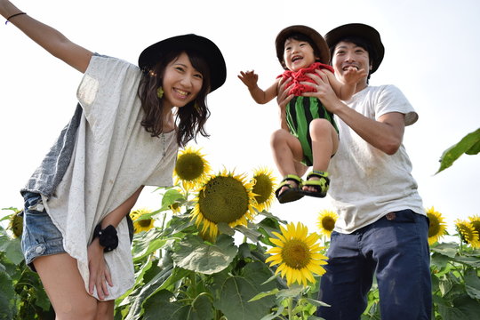 young family is smiling with sunflower field