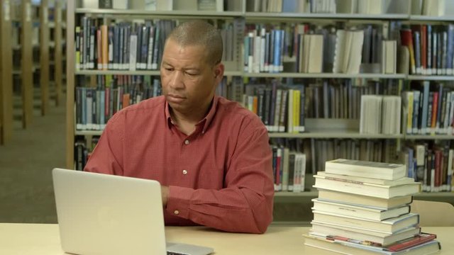 African american man using laptop in library