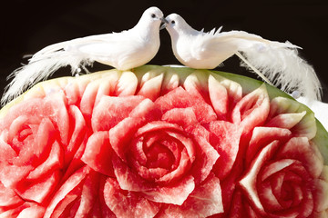 two snow-white doves sitting on the watermelon with cut flowers rose red beautiful art