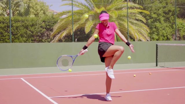 Single Woman In Pink Blouse And Sun Visor Juggling Tennis Balls On Court In Tropical Area With Racket In Hand