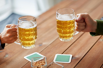 close up of hands with beer mugs at bar or pub