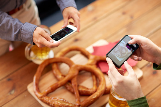close up of hands picturing pretzel by smartphone