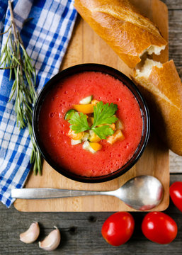 Gazpacho served in a bowl with baguette, herbs and vegetables