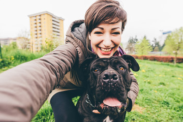 Young beautiful caucasian woman in a park outdoor taking selfie with her dog - happiness,...