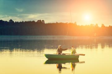 father and son catch fish from a boat at sunset - 119457364