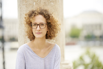 Summer day in the city. Close-up portrait of young confident woman wearing sunglasses and smiling.