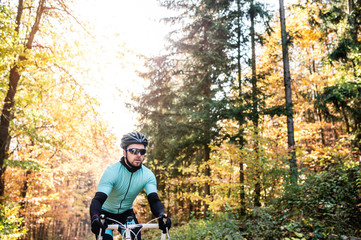 Young sportsman riding bicycle outside in sunny autumn nature