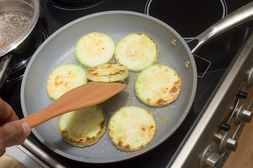 Sliced zucchini coated with eggs, flour and spices frying in a pan